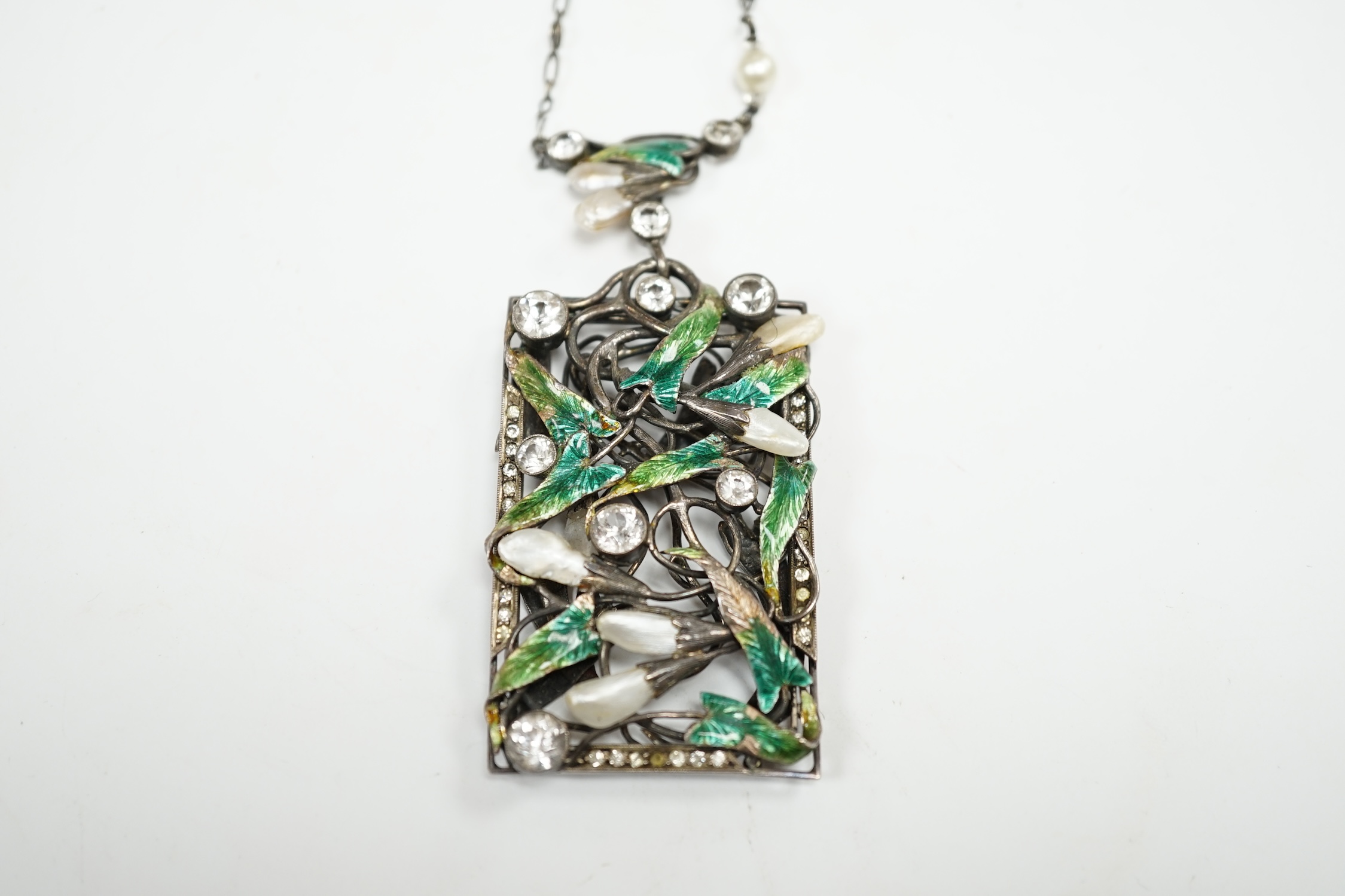 An Arts & Crafts pierced white metal, paste, simulated pearl and enamel set foliate pendant necklace, 70cm. Condition - poor